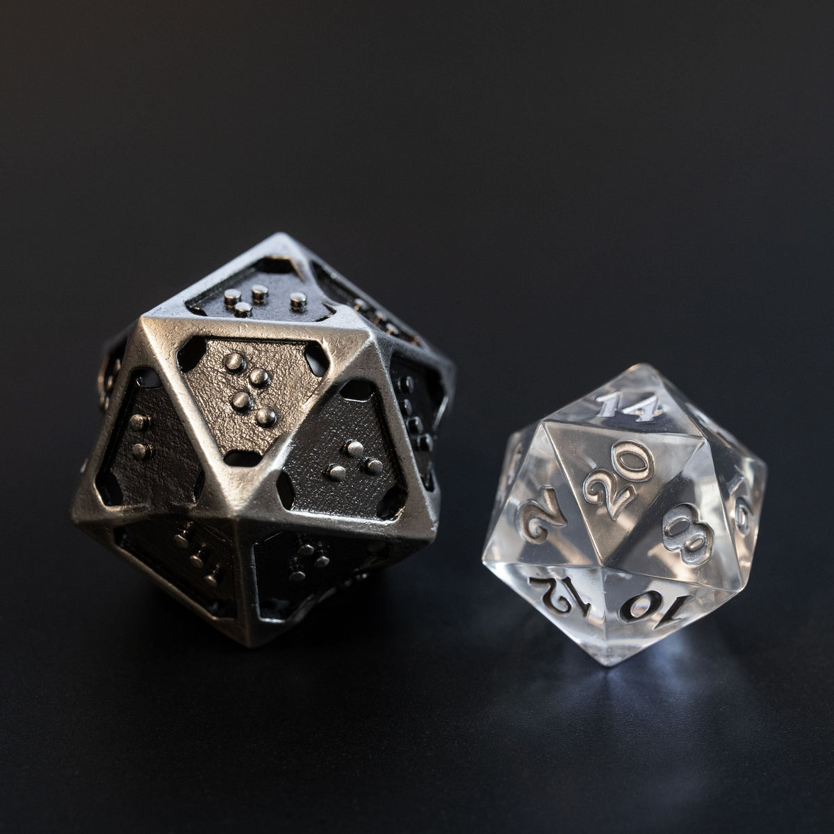 Closeup comparison of hollow metal d20 in silver ingot and translucent standard d20 is about twice the size of the standard d20